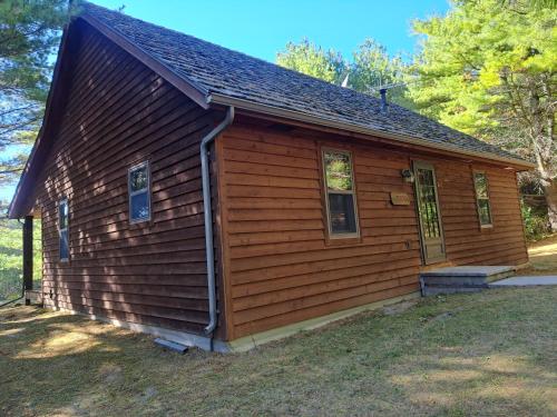 a small wooden cabin with a door and windows at Chanticleer Cabins in Sturgeon Bay
