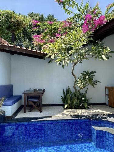 a swimming pool in a yard with a table and flowers at Stay Shark Villas Gili Air in Gili Islands