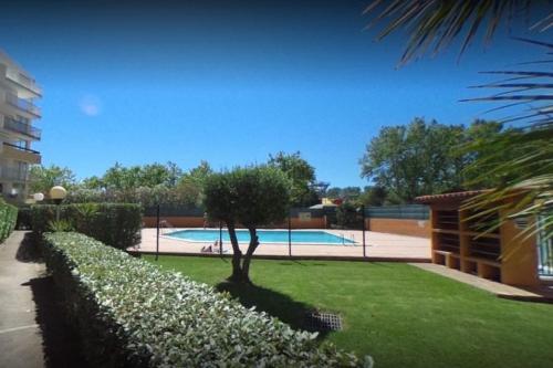 une piscine avec un arbre dans une cour dans l'établissement Sopraland 514, T2 pour 5 pers, piscine, petite vue mer, au Cap d'Agde