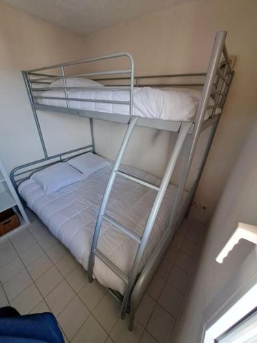 Ce lit superposé se trouve dans un dortoir doté de lits blancs. dans l'établissement Sopraland 514, T2 pour 5 pers, piscine, petite vue mer, au Cap d'Agde