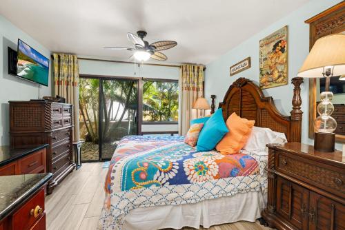 Schlafzimmer mit einem Bett mit blauen und orangefarbenen Kissen in der Unterkunft Poipu Makai Villas C1 in Koloa