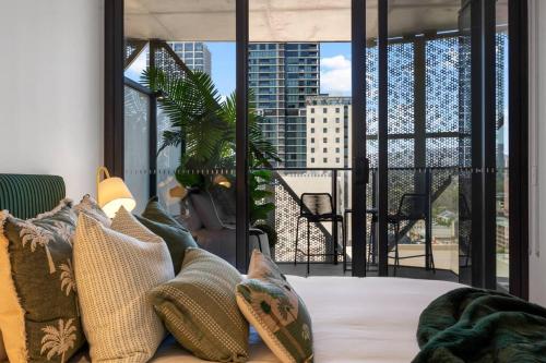 Cette chambre dispose d'un balcon avec un canapé et des oreillers. dans l'établissement Skyline Retreat - 2BR Luxury City Apartment, à Adélaïde