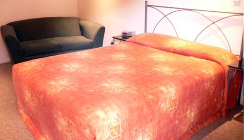 an orange bed and a chair in a room at Academy at Botany Motor Inn in Auckland