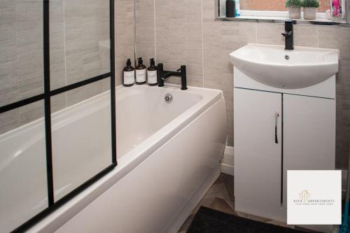 ein Badezimmer mit einer weißen Badewanne und einem Waschbecken in der Unterkunft Riya Apartments 2 Bedroom- Wifi-Free Parking in Lemington