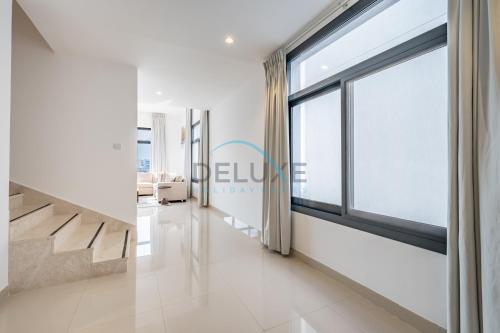a living room with a large window and a staircase at Best Deal 3BR plus maid's with Pool Perfect for Groups by Deluxe Holiday Homes in Fujairah