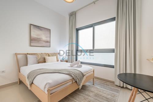 a bedroom with a bed and a table and a window at Best Deal 3BR plus maid's with Pool Perfect for Groups by Deluxe Holiday Homes in Fujairah