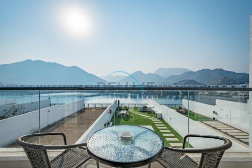 a table and chairs on a balcony with a view of mountains at Best Deal 3BR plus maid's with Pool Perfect for Groups by Deluxe Holiday Homes in Fujairah