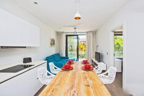 Lujoso junto a la 5th avenida 306 في بلايا ديل كارمن: مطبخ وغرفة معيشة مع طاولة وكراسي خشبية