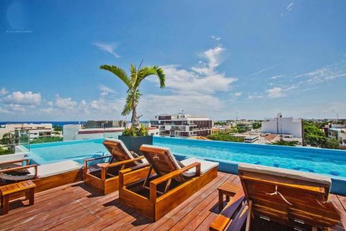 a deck with chairs and a swimming pool at Lujoso junto a la 5th avenida 306 in Playa del Carmen