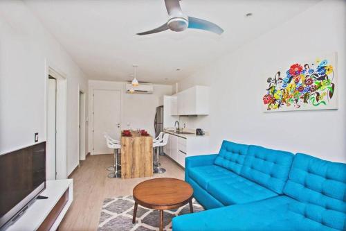 Lujoso junto a la 5th avenida 306 في بلايا ديل كارمن: غرفة معيشة مع أريكة زرقاء وطاولة