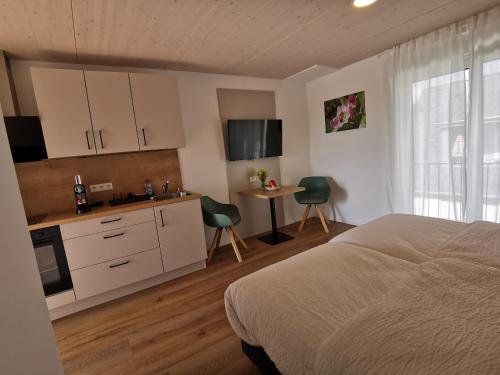 a bedroom with a bed and a kitchen with a table at Obstbau Apartment am See in Lindau