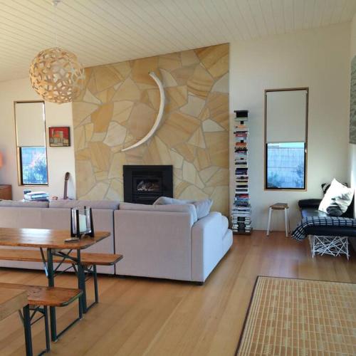a living room with a white couch and a fireplace at Sheoakes Beach House- East Coast Tas in Falmouth