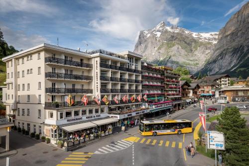 a building with a bus on a street with a mountain at Hotel Kreuz & Post Grindelwald in Grindelwald