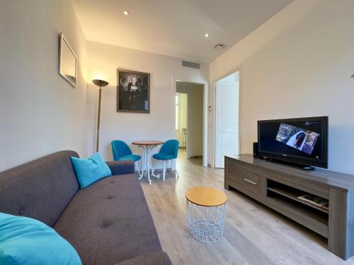 un salon avec un canapé, une télévision et une table dans l'établissement Vénus By SCLS Locations, à Cannes