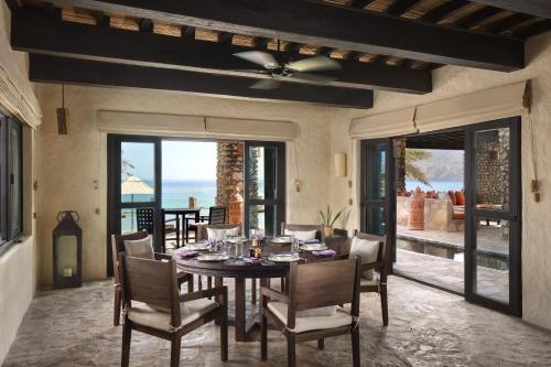 a dining room with a table and chairs and the ocean at Six Senses Zighy Bay in Dibba