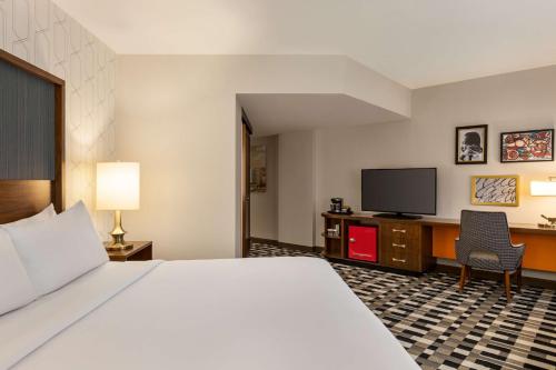 a hotel room with a bed and a flat screen tv at The American Hotel Atlanta Downtown, Tapestry Collection by Hilton in Atlanta