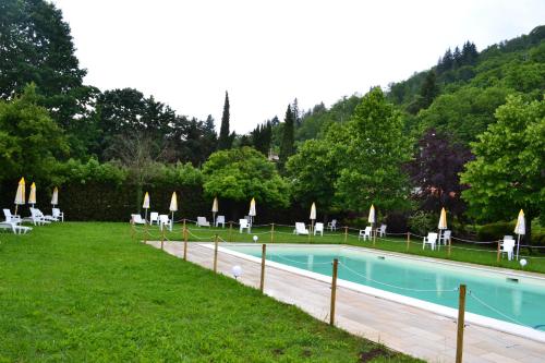 a swimming pool with chairs and umbrellas next to a field at Ai canipai in San Romano in Garfagnana