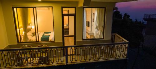a balcony of a house with three windows at night at Bob's N Barley in Dharamshala