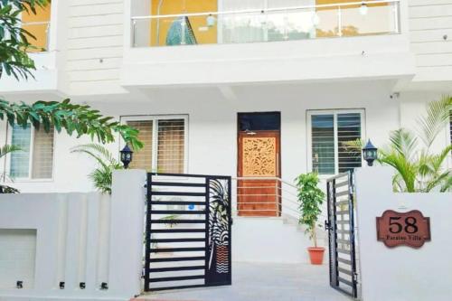 a white house with a gate and a sign at 58 Paraiso Villa in Udaipur