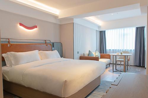 a hotel room with a large bed and a chair at Echarm Hotel Panzhihua Hubin Road in Panzhihua