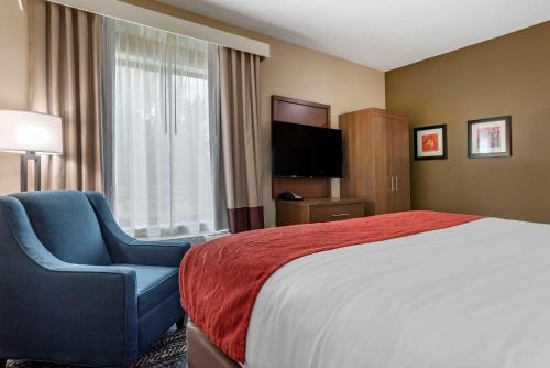 a hotel room with a bed and a chair and a television at Comfort Inn & Suites Downtown near University in Tuscaloosa