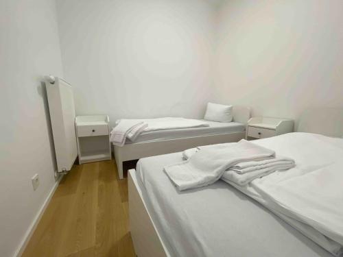 due letti in una stanza con pareti bianche e pavimenti in legno di AM1014 - Modern eingerichtete Monteurwohnung Übergangswohnung ad Amberg