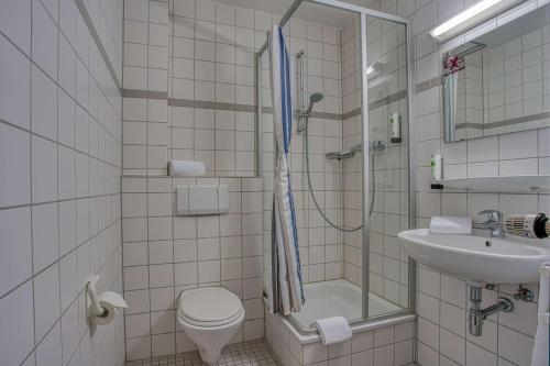 a bathroom with a shower and a toilet and a sink at Centro Hotel Böblingen, Trademark Collection by Wyndham in Böblingen