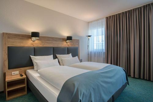 a hotel room with a large bed and a window at Centro Hotel Böblingen, Trademark Collection by Wyndham in Böblingen