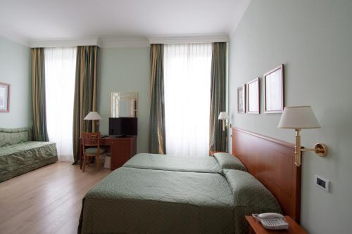 a hotel room with a bed and a desk and window at Ateneo Garden Palace in Rome