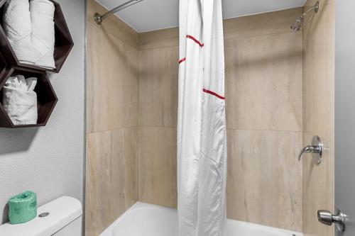 a bathroom with a shower with a white tub at HomeTowne Studios by Red Roof Richmond - Airport Sandston in Sandston