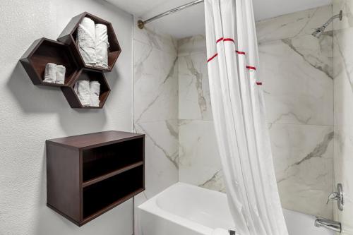 a bathroom with a shower and a sink with a shower curtain at HomeTowne Studios by Red Roof Richmond - Airport Sandston in Sandston