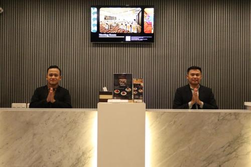 two men sitting at a counter with their hands praying at The Victoria Hotel Yogyakarta in Yogyakarta