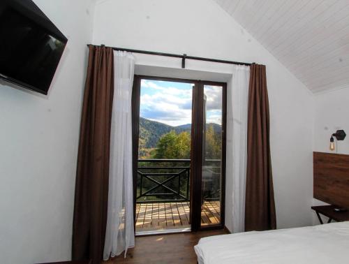 a bedroom with a door open to a balcony at Rubus resort in Yaremche