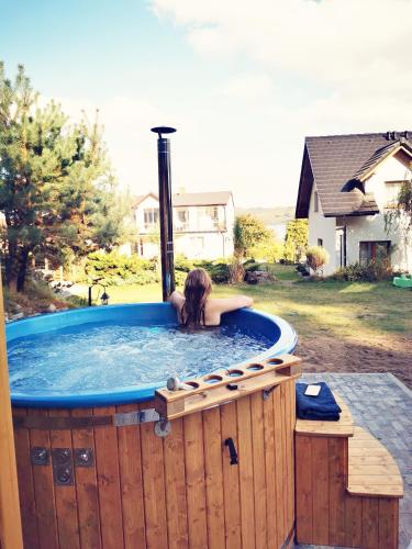 a woman laying in a hot tub in a backyard at 4 Pory Roku Apartamenty Domki Pokoje in Nadole