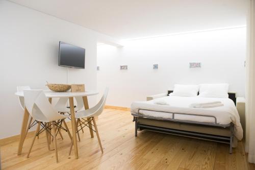 a white bedroom with a bed and a table at Páteo Saudade Lofts in Lisbon