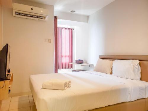 ein Schlafzimmer mit einem weißen Bett und einem Handtuch darauf in der Unterkunft Cozy Studio at Cinere Bellevue Suites Apartment By Travelio in Karangtengah