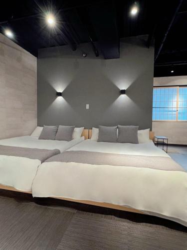 two large beds in a bedroom with lights on the wall at IKEBUKURO TOKIWA 10 BUILDING 6min walk from Ikebukuro Station Direct access to the airport in Tokyo
