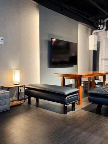 a room with a bench and a table and a tv at IKEBUKURO TOKIWA 10 BUILDING 6min walk from Ikebukuro Station Direct access to the airport in Tokyo