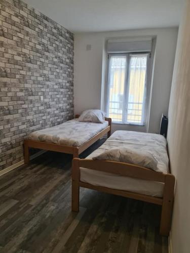 deux lits dans une chambre avec un mur de briques dans l'établissement Appartement centre du village, à Flassans-sur-Issole