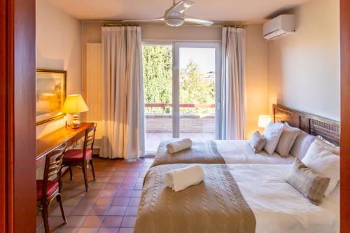 a hotel room with two beds and a desk and a window at Cigarral Valdecolomba, cerca del casco histórico in Toledo