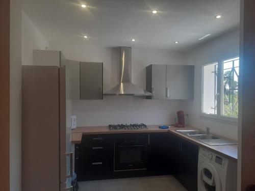 Il comprend une cuisine équipée d'une cuisinière. four supérieur à côté d'un évier dans l'établissement Villa san salvador Torreilles plage, à Torreilles