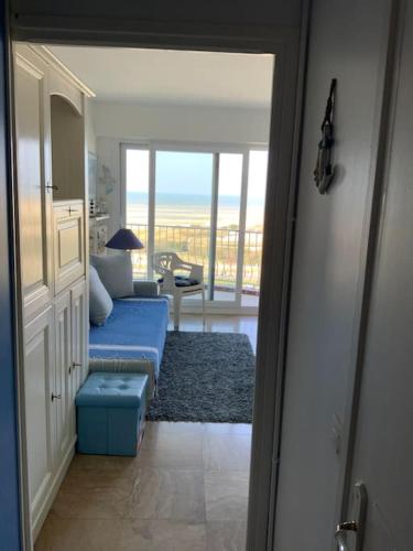 a living room with a blue couch and a view of the ocean at Studio, nid douillet, face mer 2 pers in Le Touquet-Paris-Plage