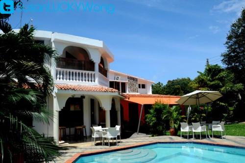 a house with a swimming pool and chairs and an umbrella at Pontoon Residences & Suites in Mombasa