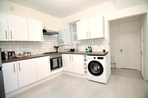 a white kitchen with a washing machine in it at London Serviced Accommodation near Tottenham Hotspurs Football Stadium Great for Contractors in London