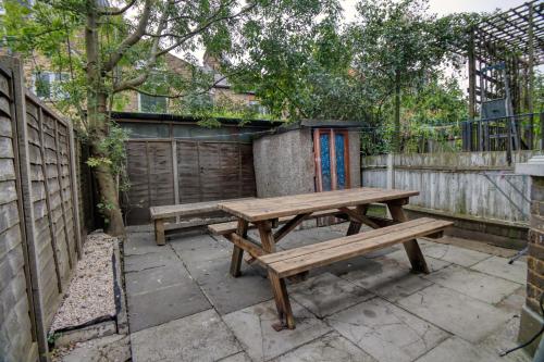 a wooden picnic table in a backyard with a fence at London Serviced Accommodation near Tottenham Hotspurs Football Stadium Great for Contractors in London