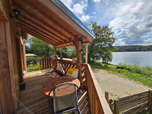 un portico di una cabina con tavolo e vista sull'acqua di Le Chalet de la Femme du Pêcheur a Peigny