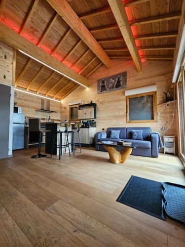 un soggiorno con un divano blu e una cucina di Le Chalet de la Femme du Pêcheur a Peigny