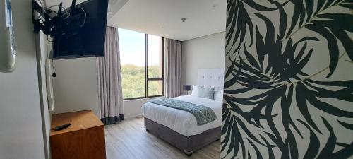 ein Hotelzimmer mit einem Bett und einem Fenster in der Unterkunft Zimbali Suites 505 in Ballito