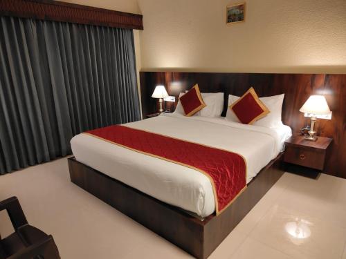 a large bed in a hotel room with two lamps at Hotel Badami Court in Badami