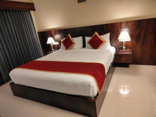 a large bed in a hotel room with two lamps at Hotel Badami Court in Badami